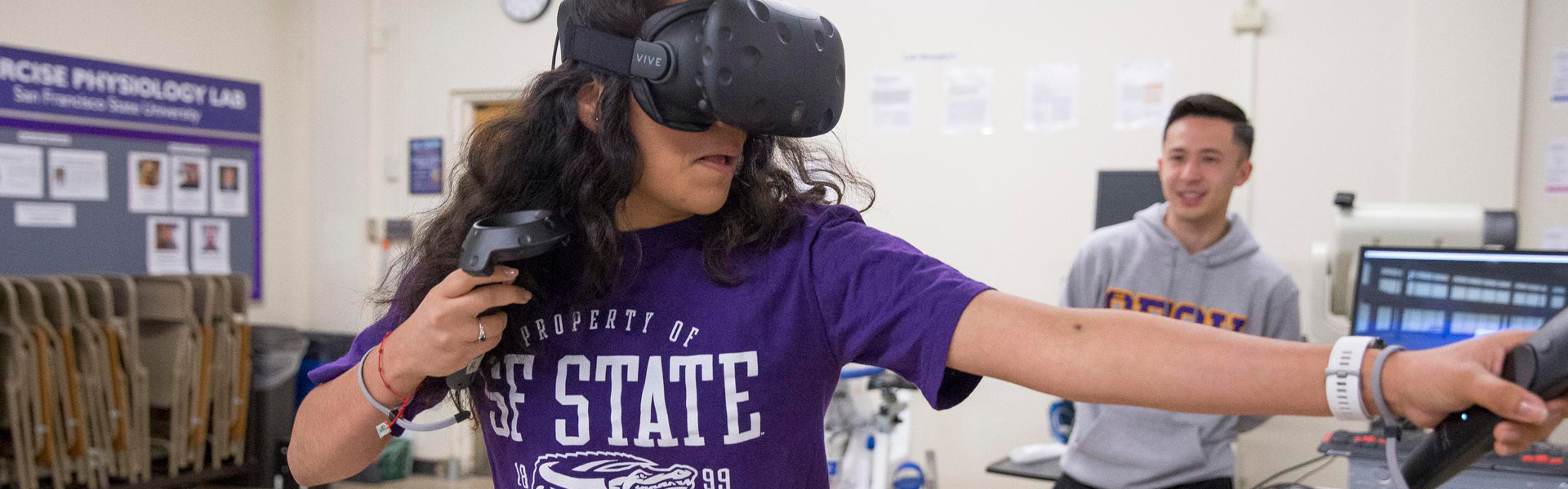 Female student wearing virtual reality headset with smiling student looking on
