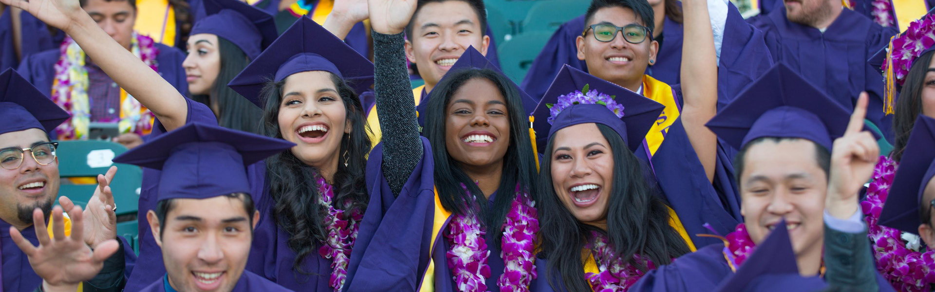 SF State students smiling wearing commencement regalia