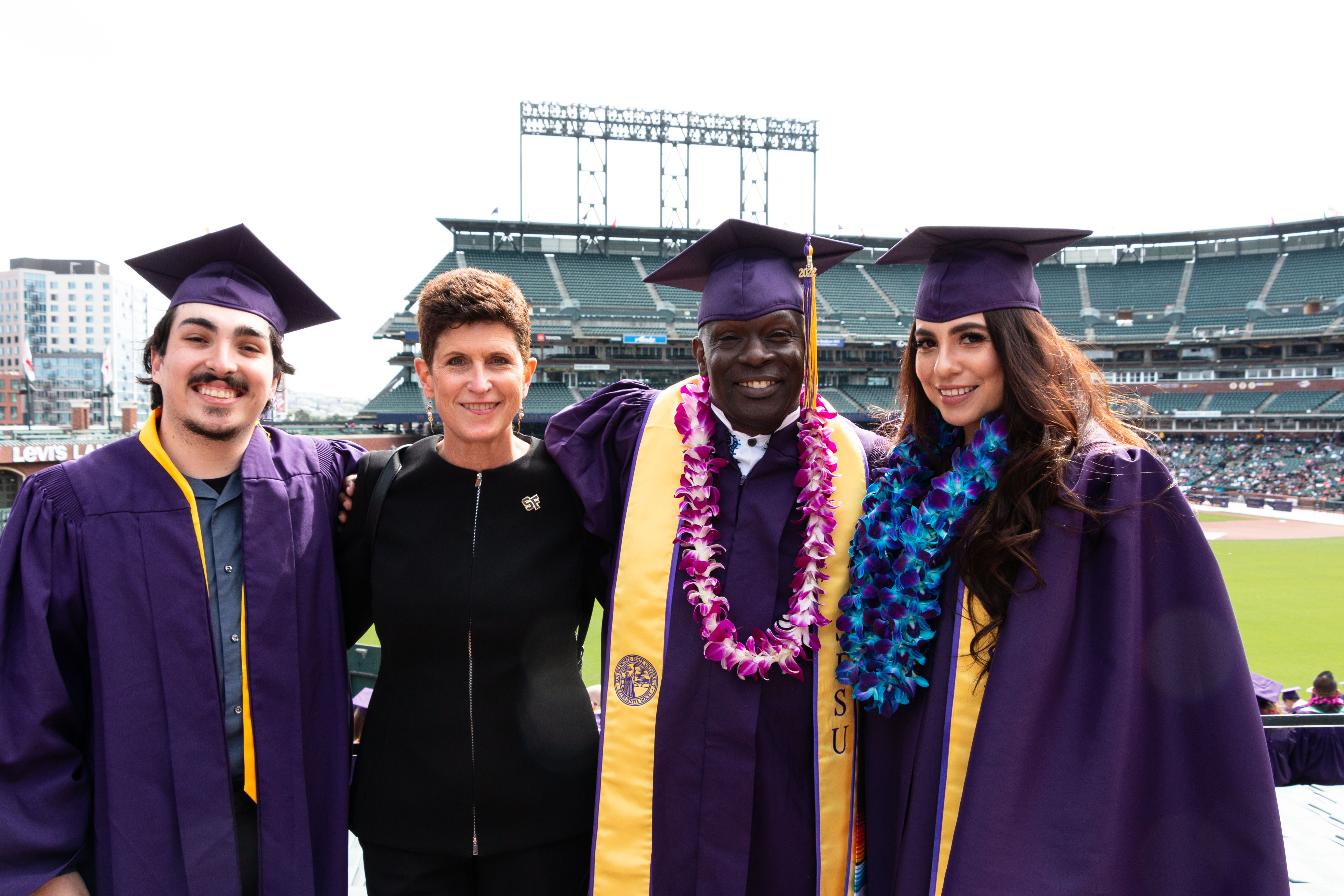 President Mahoney with three SF State graduates at Oracle Park.