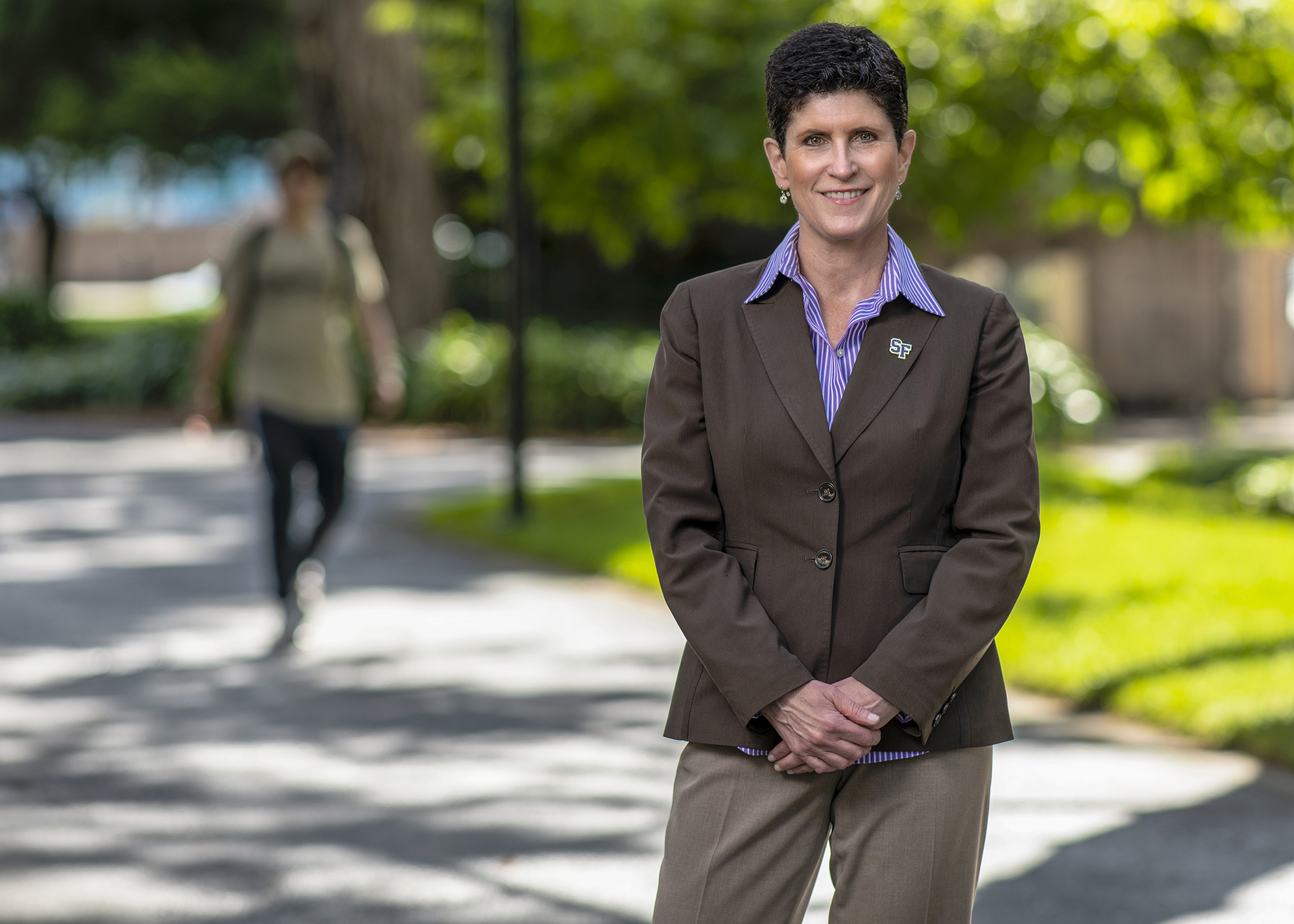 Lynn Mahoney standing on a campus walkway, smiling