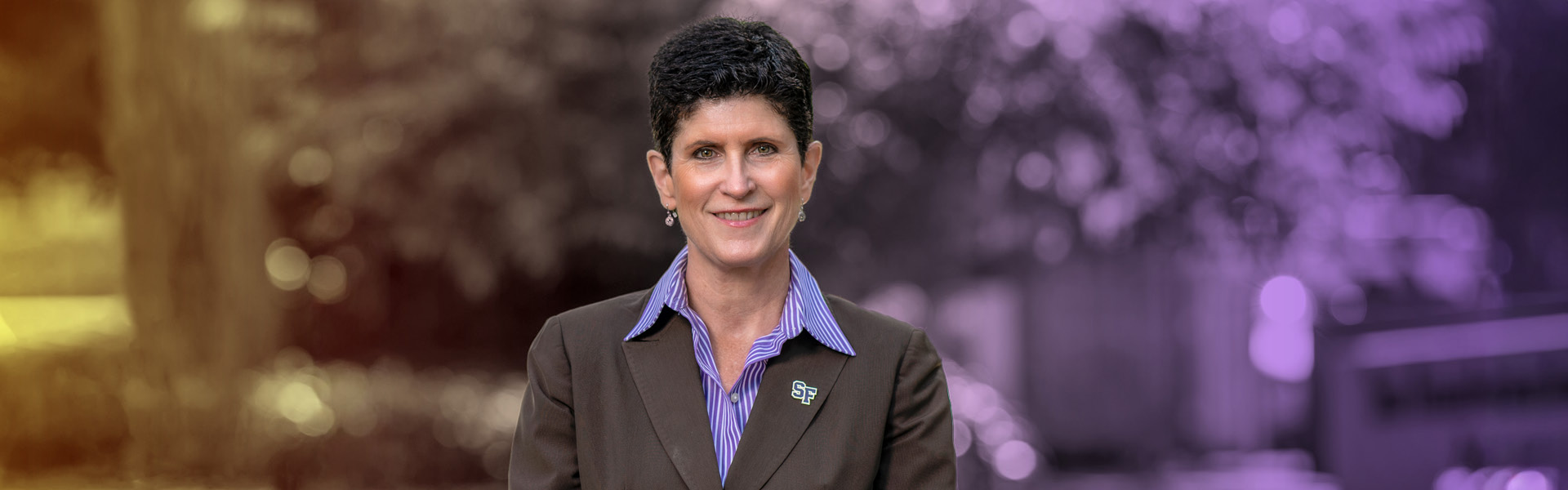 President Lynn Mahoney outside on the SFSU campus with a purple and gold background