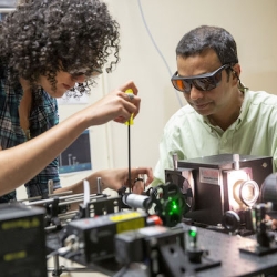 Faculty members working on an electronic device together