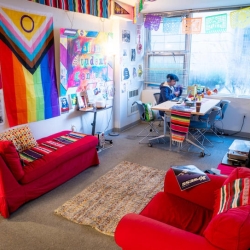Red couches and colorful artwork on the walls inside the Latinx Student Center